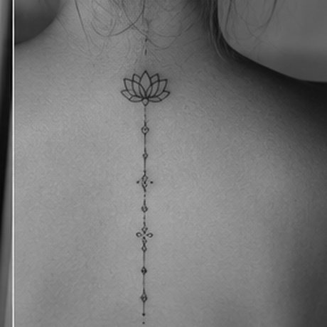 Fine line lotus and ornamental spine tattoo