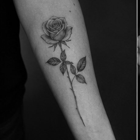 Fine line rose tattoo on a forearm in black ink